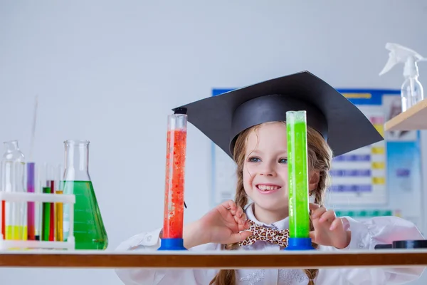 Smiling little chemist posing with colorful flasks — Stock Photo, Image
