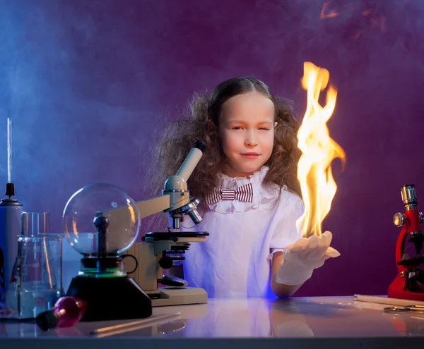 Smiling girl shows chemical trick - fire in palm — Stock Photo, Image