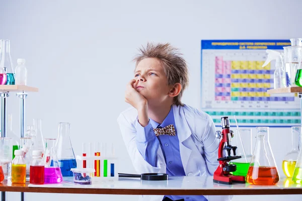 Nadenkend schattige jongen poseren onder chemische apparatuur — Stockfoto