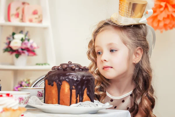 Adorable little girl looks thoughtfully at cake — Stock Photo, Image