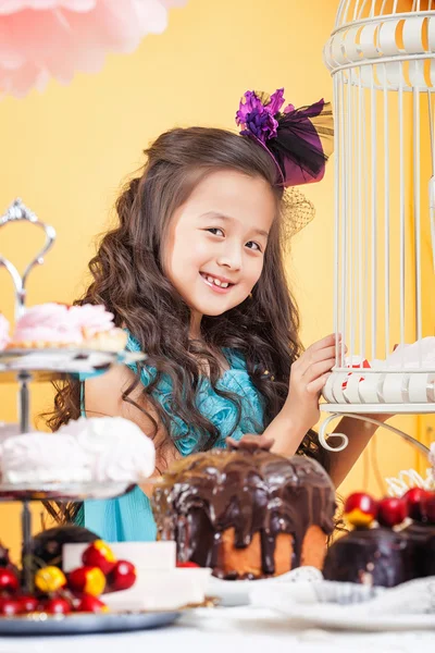 Malá kudrnatá bruneta pózuje s sladkosti — Stock fotografie
