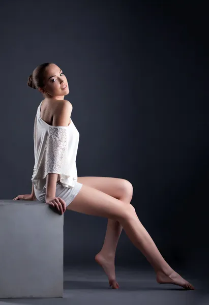 Aantrekkelijke jonge model poseren zittend op kubus — Stockfoto