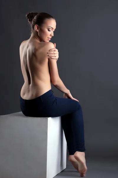 Ganska smal kvinna poserar topless sitter på kub — Stockfoto