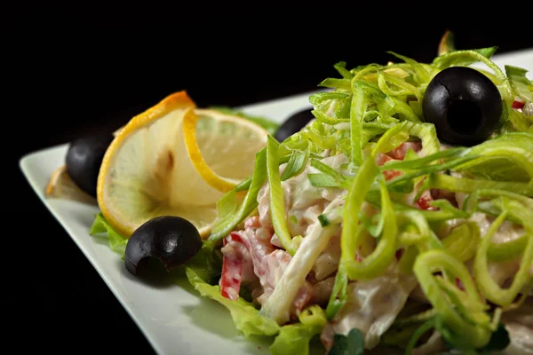 Delicious salad garnished leek, lemon and olives — Stock Photo, Image