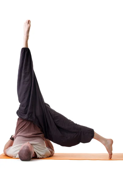 Flexible man doing yoga in loose-fitting clothing — Stock Photo, Image