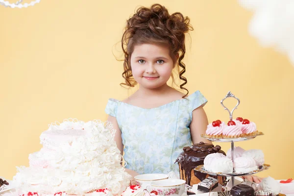 Pretty smiling girl posing at table with desserts — Stock Photo, Image