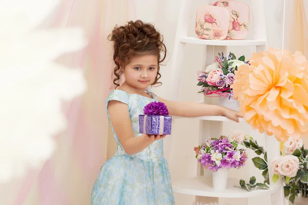 Linda chica posando con caja de regalo en estudio decorado — Foto de Stock