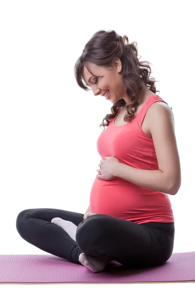 Sorridente donna incinta abbraccia pancia durante lo yoga — Foto Stock