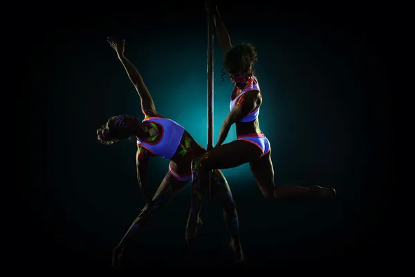 Pair of sexy pole dancers under UV light — Stock Photo, Image