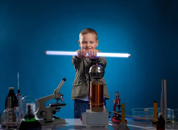 Энтузиастичный школьник держит светящуюся лампу в лаборатории — стоковое фото