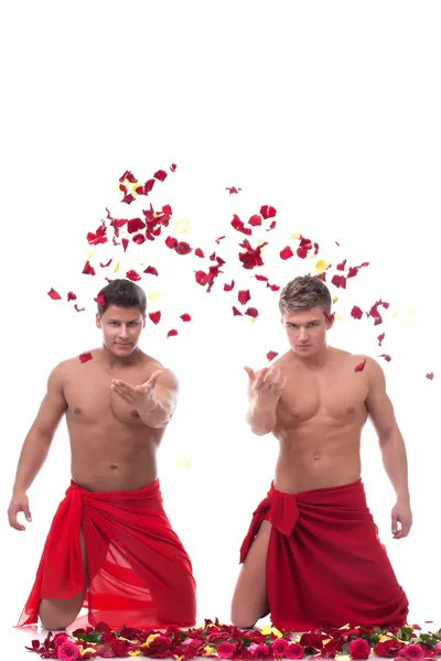 Beautiful muscular young men throw rose petals — Stockfoto