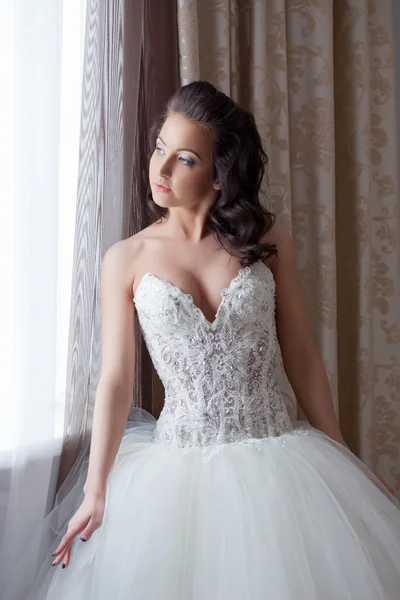 Hübsche junge Braut posiert am Fenster im Hotelzimmer — Stockfoto