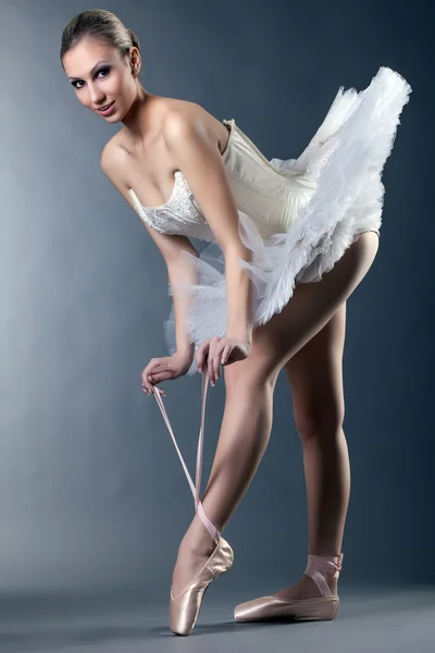 Charming female ballet dancer posing tying pointe — Stock Photo, Image