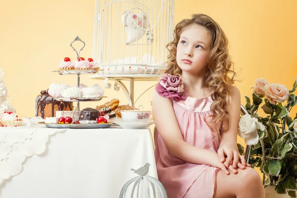 Menina pensativa posando à mesa com bolos — Fotografia de Stock