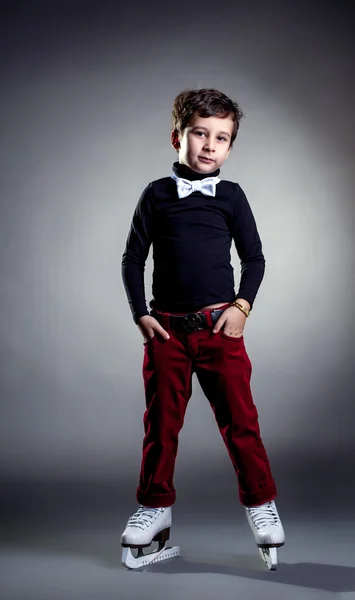 Niño vestido de moda posando patinaje sobre hielo en el estudio —  Fotos de Stock