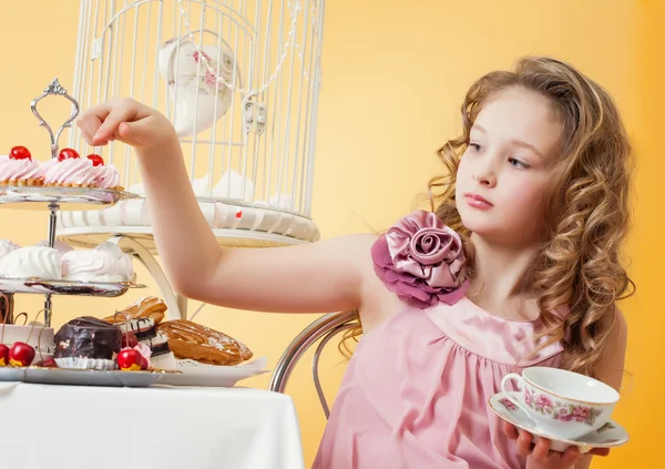 Akıllıca giymiş küçük bir kız pastası ile çay içme — Stok fotoğraf