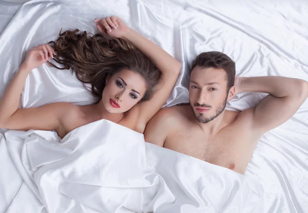 Bilden av unga heterosexuella par poserar i sängen — Stockfoto