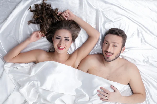 Fröhliches heterosexuelles Paar posiert im Bett — Stockfoto