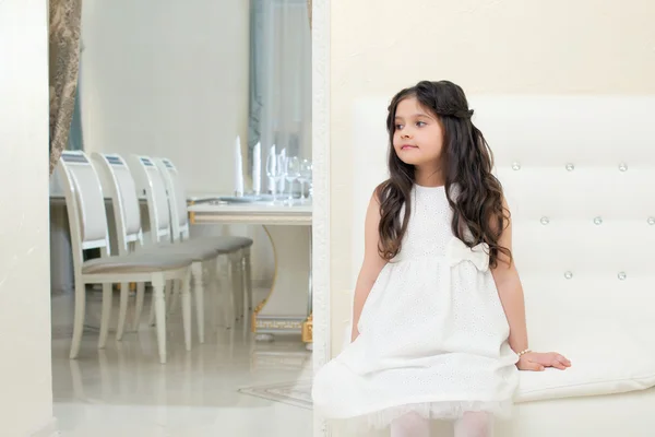 Pretty little girl posing while sitting on couch — Stock Photo, Image