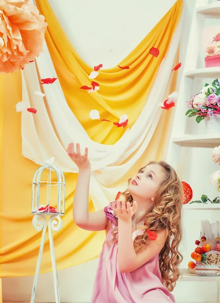 Mooi curly-haired meisje speelt met bloemblaadjes — Stockfoto