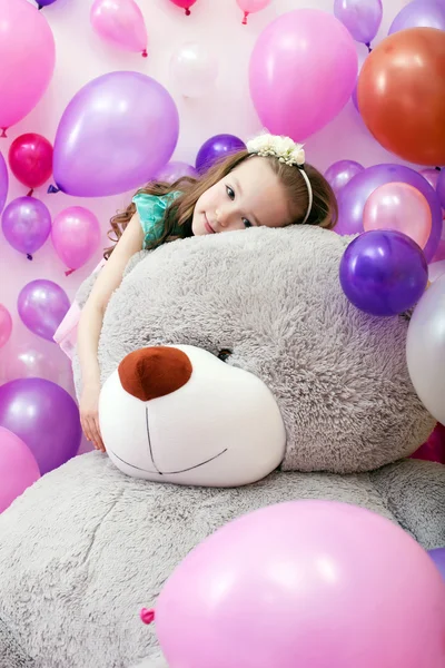 Linda chica rizada posando acostada sobre un gran oso de peluche — Foto de Stock