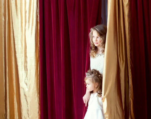 Beautiful girls look out from behind scenes — Stock Photo, Image