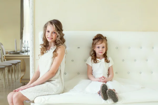 Smart Girls posieren vor der Kamera, während sie auf dem Sofa sitzen — Stockfoto