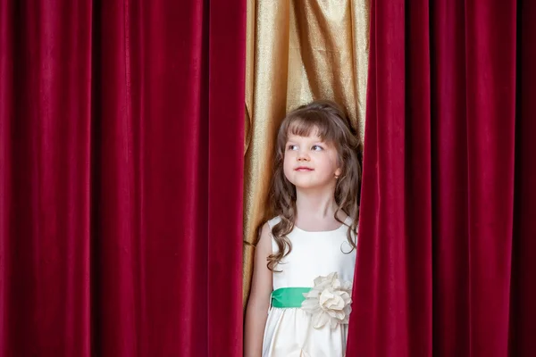 Pretty little brunette posing on curtain backdrop — Stock Photo, Image