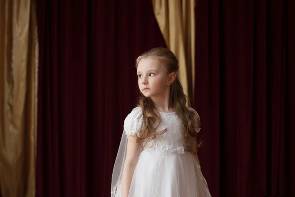 Girlie in witte jurk die zich voordeed op gordijn achtergrond — Stockfoto