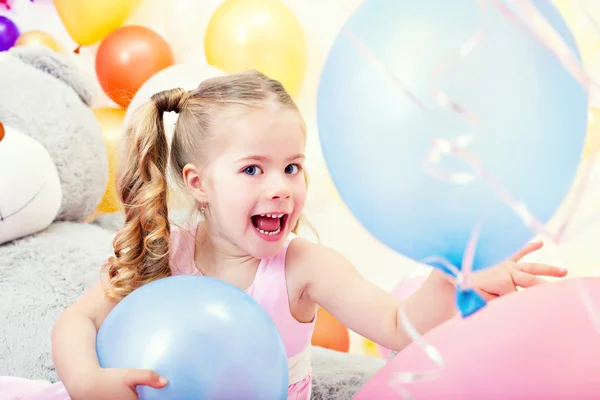 Fröhliches kleines Mädchen posiert mit blauen Luftballons — Stockfoto