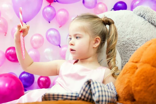 Funny little girl attentively looks on lollipop — Stock Photo, Image