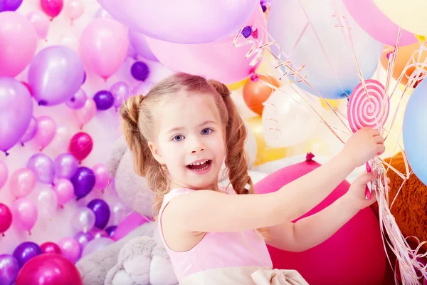 Merry little girl posing with bunch of balloons — Stock Photo, Image