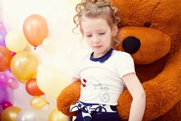 Leuk meisje poseren in omhelzing met grote teddybeer — Stockfoto