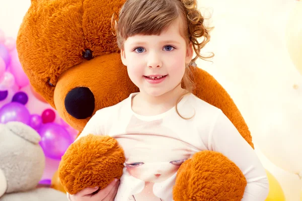 Mooi meisje poseren in armen van grote teddybeer — Stockfoto