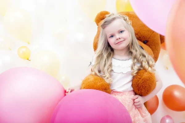 Smiling blonde girl playing with teddy bear — Stock Photo, Image