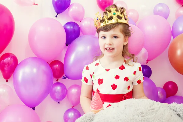 Söt flicka som poserar i kronan på ballonger bakgrund — Stockfoto