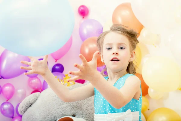 Funny little girl plays with balloon in studio — Stock Photo, Image