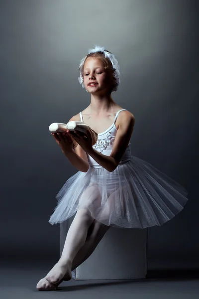 Lächelnde kleine Ballerina posiert auf Würfel sitzend — Stockfoto