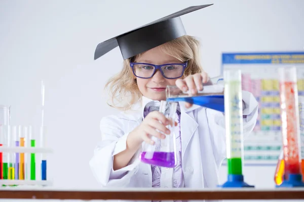 Curious schoolgirl pouring reagent into flask — Stock Photo, Image