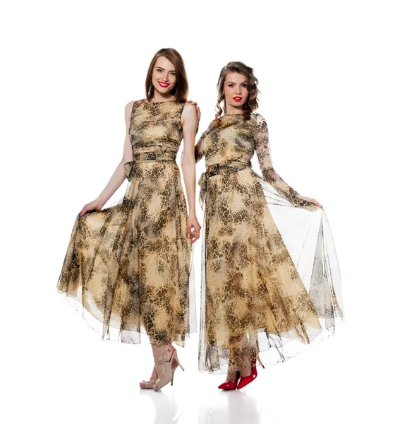 Charmante vrouwen poseren in jurken van dezelfde stof — Stockfoto