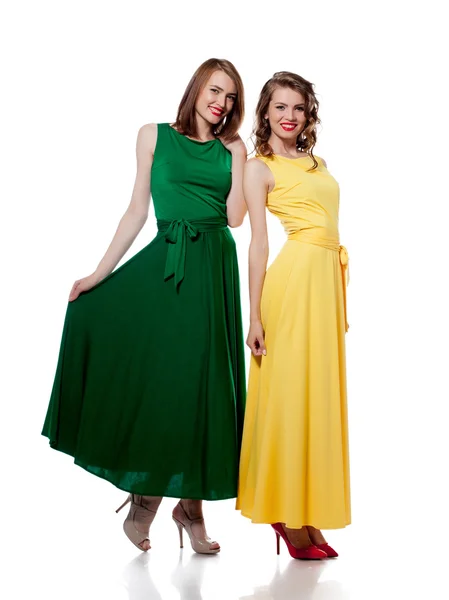 Lachende meisjes poseren in stijlvolle kleurrijke jurken — Stockfoto
