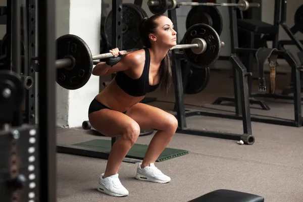 Hermosa chica haciendo ejercicio en cuclillas con barra — Foto de Stock