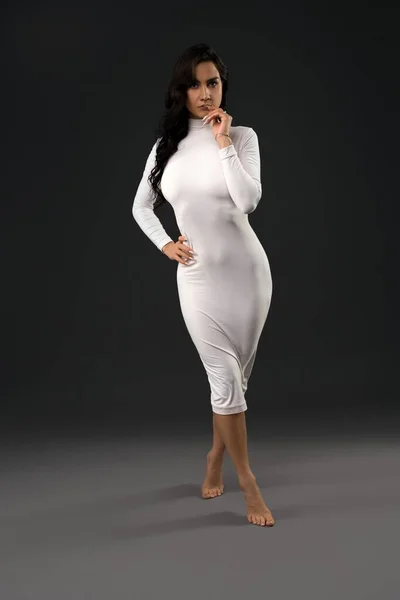 Очаровательная женщина в белом платье смотрит в камеру — стоковое фото