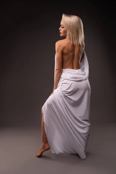 Blondýnka zabalená v bílé látce s nahou páteří — Stock fotografie