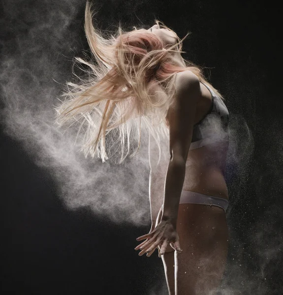 Блондинка в спортивной одежде, прыгающая в облаке пыли — стоковое фото