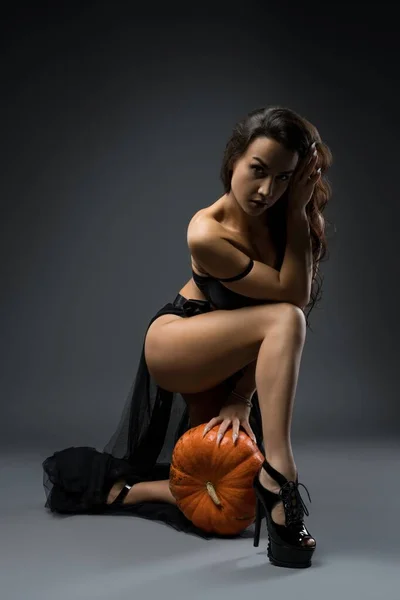 Provocative woman in underwear and black skirt with pumpkin — Stock Photo, Image