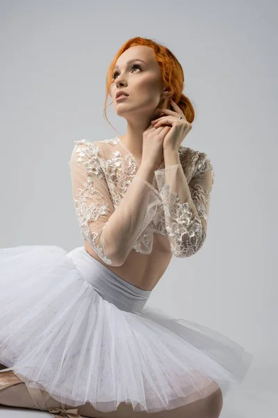 Graceful female ballet dancer sitting on floor and looking up — Stock Photo, Image