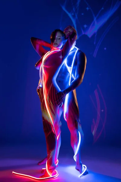 Naked couple wrapped with neon ropes and standing together — Stock Photo, Image