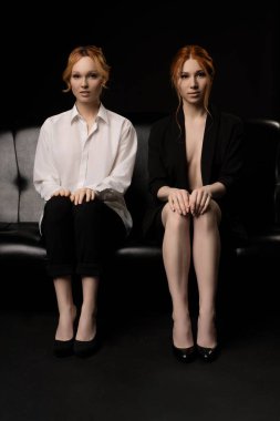 Kendine güveni tam, kızıl saçlı, şeffaf beyaz gömlekli, çıplak vücutlu, siyah takım elbiseli, ciddi bir bayan menajer.