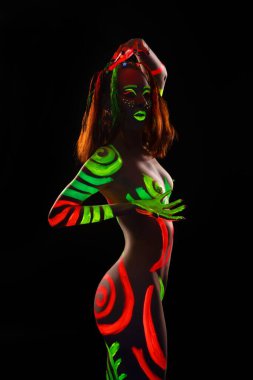 Üstsüz kadın portresi. Ultraviyole kordonla karanlıkta dans ediyor.